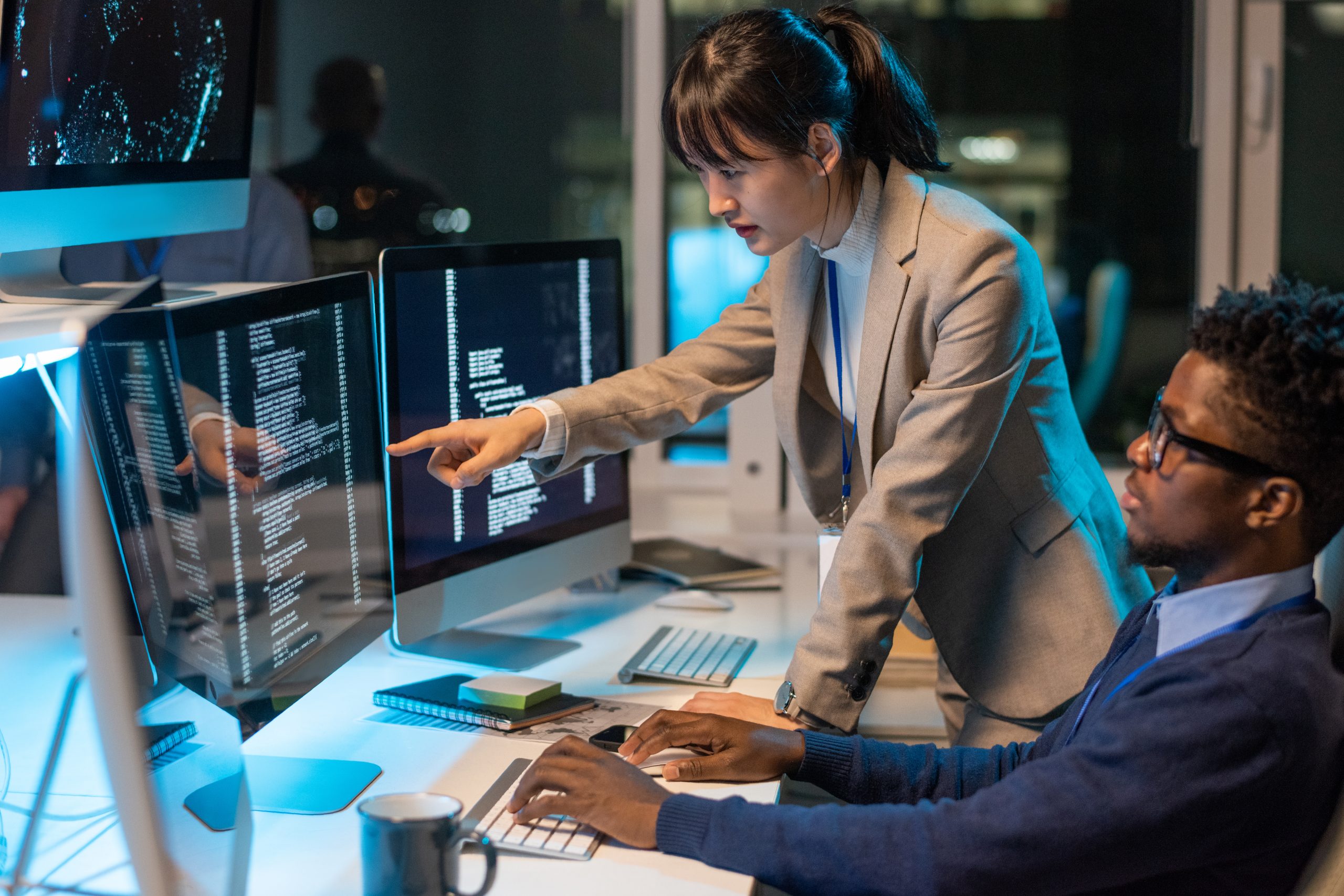 Young Asian female it-engineer pointing at data on computer screen